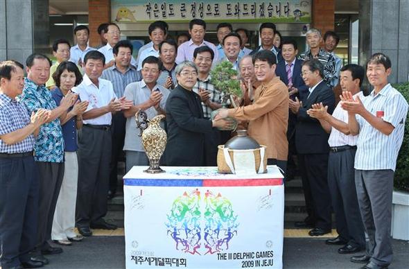  7일 오전 제주시 애월읍사무소에서 열린 제3회 제주세계델픽대회 성수 봉송행사에서 강문칠 델픽조직위원회 부위원장(가운데 왼쪽)이 성수를 부은 소나무 분재를 고태민 애월읍장에게 전달하고 있다.  제주/연합뉴스