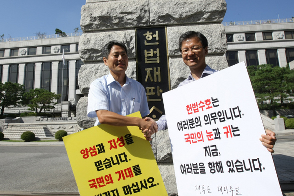 천정배 전 법무부 장관(오른쪽)이 9일 오전 서울 재동 헌법재판소 앞에서 ‘언론악법 원천무효와 헌법재판소의 바른 결정을 촉구하는 릴레이 1인 시위’를 벌인 뒤 다음 순서인 신학림 신문발전위원과 교대하며 악수하고 있다.  이정아 기자 leej@hani.co.kr