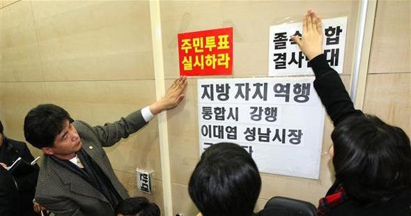 경기 성남시 의회 야당 의원들이 21일 오전 성남·광주·하남시 통합 의결안의 의회 상정을 막으려고 시의회 본회의장 출입문을 쇠사슬로 묶은 채 통합안의 주민투표를 주장하고 있다.  성남/연합뉴스