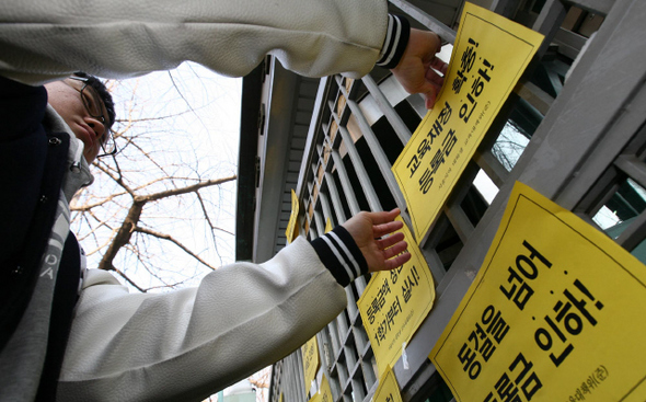 광운대·덕성여대 등 서울지역 10개 대학 총학생회장단이 7일 오전 서울 종로구 세종로 정부중앙청사 뒷문에서 ‘등록금 상한제’ 실시와 등록금 인하를 촉구하는 기자회견을 연 뒤 구호가 적힌 종이팻말을 청사 벽에 붙이고 있다.  이종근 기자 root2@hani.co.kr