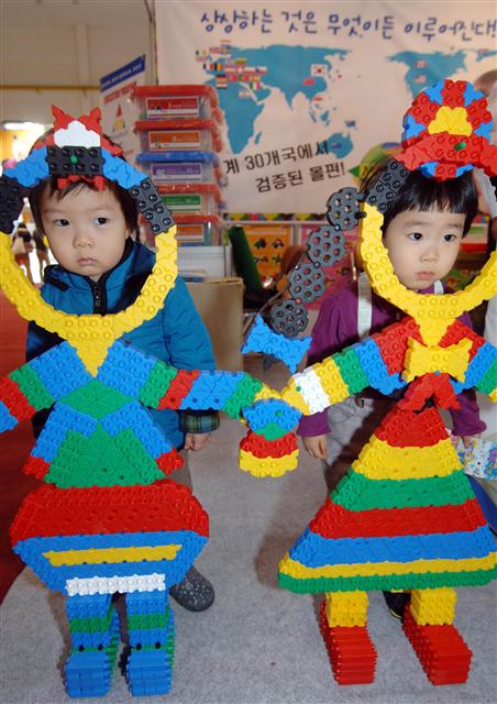  21일 부산 벡스코에서 열린 부산국제어린이유아교육전을 찾은 어린이들이 완구업체가 마련한 장난감을 배경으로 기념사진을 찍고 있다. 오는 24일까지 열리는 이번 행사에는 60여 개 업체가 참여해 유아용 음악교육 프로그램 등 다양한 교육상품을 선보인다.  부산/연합뉴스