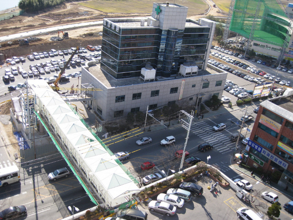 울산 동강병원 본관 위에서 내려다본 육교. 아래쪽에 차량이 몇 대 보이는 곳이 본관 주차장이고 차량이 많이 보이는 맞은편이 종합건강검진센터 주차장이다. 검진센터 쪽의 승강기를 타고 내려가면 223대를 댈 수 있는 주차장으로 바로 갈 수 있다. 육교 20여m 앞에 보이는 흰선들은 건널목이다. 