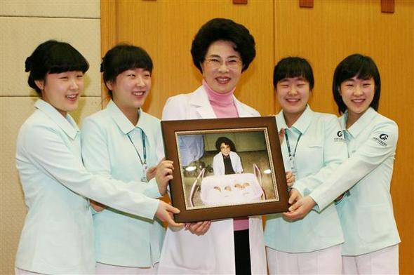 가천의대 길병원 이길여 이사장이 16일 네쌍둥이 자매에게 1989년 1월 이들이 태어날 때 사진 을 담은 액자를 선물하고 있다. 왼쪽부터 황슬·설, 이 이사장, 솔·밀씨.  사진 길병원 제공