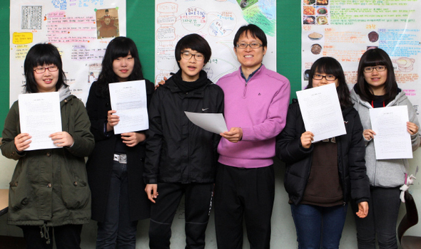 중랑중학교 김태훈 교사가 17일 오전 교실에서 학생들과 함께 하고 있다. 학생들이 들고 있는 것은 기존 성적표 대신 김교사가 직접 만든 행복성적표. 박종식 기자 anaki@hani.co.kr