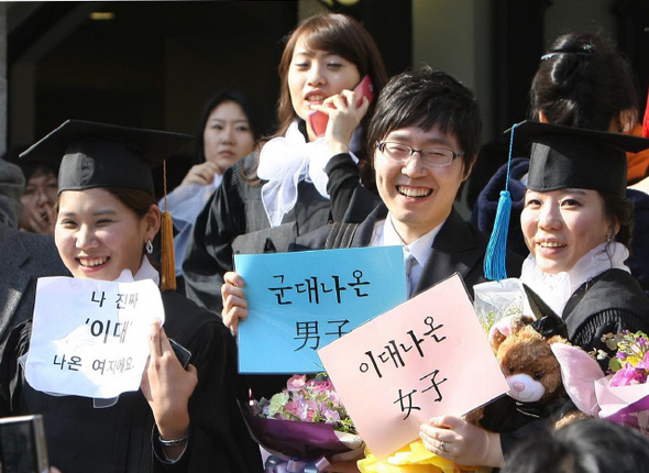 22일 오후 서울 서대문구 이화여대에서 열린 학위수여식에서 졸업생들이 남자 축하객과 함께 익살스런 문구가 적힌 종이를 손에 든 채 기념사진을 찍고 있다.  이종근 기자 root2@hani.co.kr