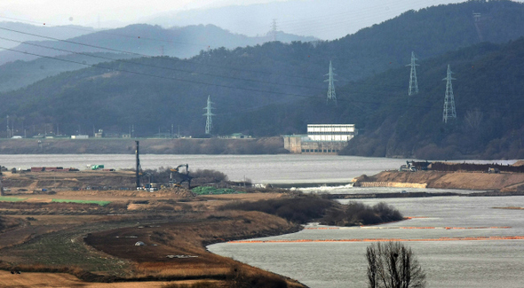 대구시민들이 마실 식수를 취수하고 있는 대구 달성군 다사읍 죽곡정수장(철탑에 둘러싸인 하얀 건물)이 마주 보이는 곳에서 15일 오전 크레인과 굴착기를 비롯한 중장비 등이 강정보 가물막이 공사를 벌이고 있다.  대구/이종근 기자 root2@hani.co.kr