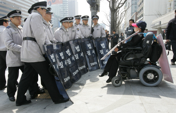 ‘420장애인차별철폐공동투쟁단’ 소속의 한 장애인이 8일 오전 서울 세종로 세종문화회관 앞에서 ‘장애인 활동보조 권리보장’을 요구하며 광화문광장으로 가려 하자 경찰이 막고 있다. 투쟁단은 지난 2일부터 장애인 활동보조 권리보장을 위한 10만인 서명운동을 시작했다.  김태형 기자 xogud555@hani.co.kr