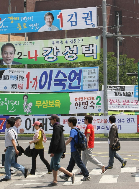 유권자의 마음을 단박에 사로잡으려는 후보들의 공약과 애절한 마음이 담긴 펼침막이 전국 도로변에 내걸렸다. 6·2 지방선거 공식 선거운동이 시작된 가운데, 21일 오후 서울 성북구 혜화동 교차로에서 시민들이 각 후보들의 펼침막이 걸린 건널목을 건너고 있다.  이종근 기자 root2@hani.co.kr