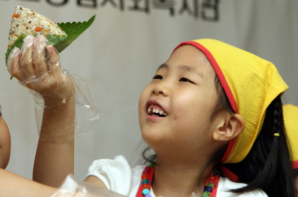 6일 오전 서울 서초구 잠원동 반포종합사회복지관에서 서울사회복지공동모금회 주최로 열린 ‘사랑의 도시락 봉사’ 행사에 참가한 한 어린이가 삼각김밥을 만들며 즐거워하고 있다. 이날 만들어진 도시락은 사조해표가 기부한 선물세트와 함께 서초구내 기초생활수급자 가정에 전달됐다. 신소영 기자 <A href="mailto:viator@hani.co.kr">viator@hani.co.kr</A>
