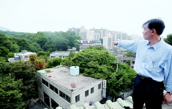  14일 오후 서울 성북구 정릉 앞 재개발 예정지에서 주민인 권영일씨가 멀리 보이는 아파트 단지처럼 개발될 자신의 동네를 가리키고 있다. 신소영 기자 <A href="mailto:viator@hani.co.kr">viator@hani.co.kr</A>