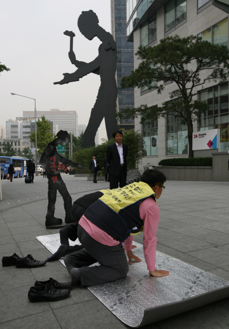 흥국생명 해고자들 ‘수사기원 108배’ 이형철 전국생명보험노조 흥국생명해고자복직투쟁위원회 의장(오른쪽 엎드린 이)과 해고자들이 20일 오전 서울 종로구 흥국생명 광화문 본사 앞에서 ‘태광그룹 계열사 각종 불법 및 편법 의혹’을 검찰에 고발하기에 앞서 기자회견을 한 뒤 철저 수사 등을 기원하는 108배를 하고 있다. 건물 앞의 커다란 조형물은 ‘망치질하는 사람’(해머링 맨)이고 작은 조형물은 해고자들이 해머링 맨을 풍자해 만든 ‘해고링 맨’이다. 
  이종근 기자 root2@hani.co.kr