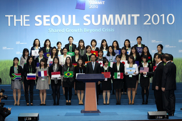 이명박 대통령이 서울 주요 20개국(G20) 정상회의 준비상황을 점검하기 위해 지난 6일 서울 삼성동 코엑스 행사장을 방문해 정상들이 기념사진을 찍는 장소인 오디토리움에서 참가국의 깃발을 든 자원봉사자들과 예행연습을 하고 있다.   청와대사진기자단