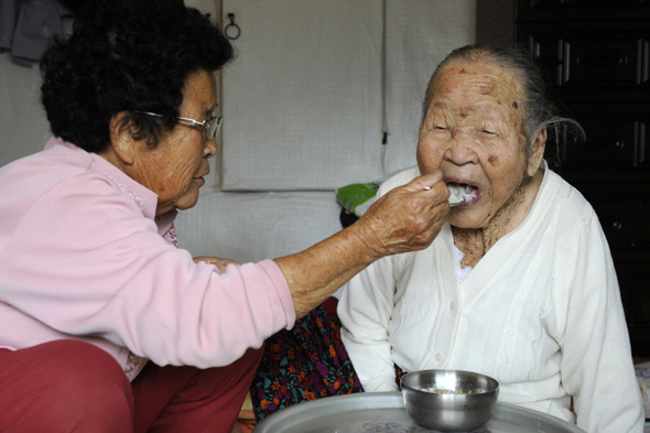 경북 청송군 부동면 신점리에 사는 김정자씨(80)가 103세의 노모 황수미 할머니에게 밥을 떠먹이고 있다. 한국전쟁 때 친정아버지를 여읜 뒤 홀로된 친정어머니가 안타까웠으나 자신도 15살에 결혼해 여섯 자식을 낳아 기르느라 돌봐드릴 수가 없었다고 했다. 이제 자식들을 모두 출가시킨 김씨는 자신도 홀몸이 된 뒤 15년 전부터 친정 어머니를 모셔다 수발을 하고 있다. 인근 야산에서 지게로 땔나무를 주워다가 군불을 때서 그 물로 몸을 씻기고, 거동이 불편해 방에 누워만지내는 어머니의 세끼 밥상을 모두 직접 챙기는가 하면 대·소변을 받아내는 등 효심 지극한 노모녀의 모습이 정겹다.  
 청송/강재훈 선임기자 khan@hani.co.kr