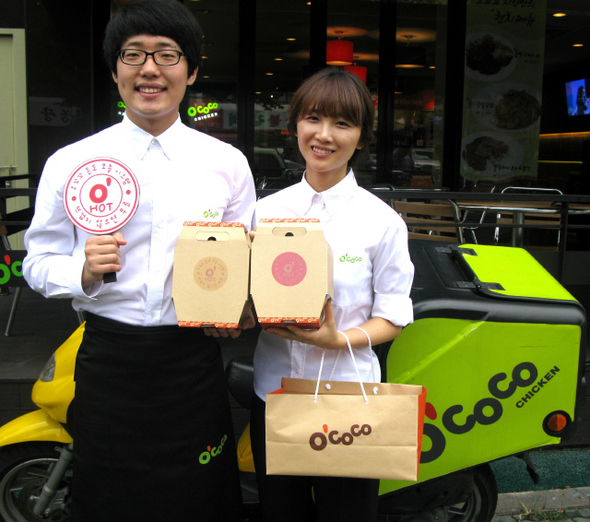 신송의 치킨 브랜드인 ‘오꼬꼬’(O’COCO) 직원들이 단열 효과를 높인 골판지 재질의 포장 상자를 들고 있다. 이 상자는 내용물이 75℃를 넘으면 ‘오핫’(O’hot)이라고 쓴 온도 스티커가 나타난다.  신송 오꼬꼬 제공