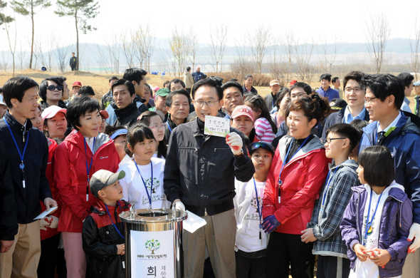  이명박 대통령이 제66회 식목일인 5일 오전 경기 여주군 대신면 이포보 상류 쪽 한강살리기 3공구 당남지구에서 지역 어린이들과 ‘희망의 숲’ 나무 심기 행사를 마친 뒤, 타임캡슐에 넣을 ‘녹색성장’이라고 쓴 메시지를 들어 보이고 있다. 이 대통령은 “여기 와보면 강이 되는대로 (범람)했었는데 지금은 정비가 싹 돼서 천지개벽한 것 같다”고 말했다.  청와대 사진기자단