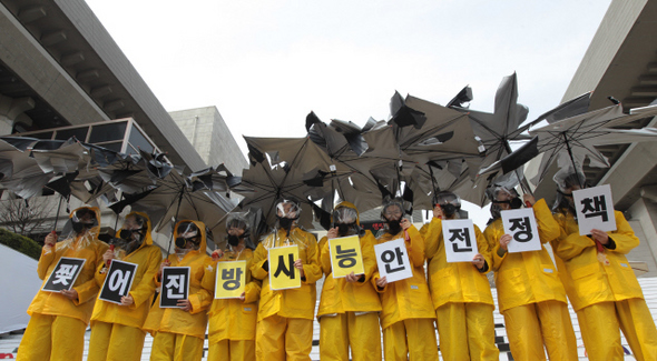 “찢어진 방사능 안전 정책”=한국환경회의와 핵발전정책전환 공동행동 회원들이 지구의 날을 하루 앞둔 21일 오전 서울 종로구 광화문 세종문화회관 앞에서 방독면을 쓴 채 찢어진 우산을 들고 정부의 방사능 안전 대책을 비판하는 내용의 손팻말을 들어 보이고 있다.  신소영 기자 viator@hani.co.kr