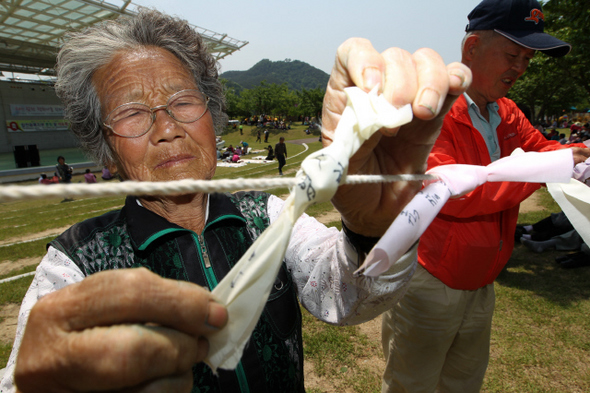 15일 오후 경남 합천군 황강 강변공원 야외공연장에서 열린 ‘원폭 피해자 및 가족과 함께하는 나들이-2011 합천 평화나눔 한마당’에서 원폭 1세대 피해자들이 소원을 적은 쪽지를 줄에 매달고 있다. 이날 행사장에서는 원폭 피해자와 2·3세 환우들의 문제 해결을 위한 조례 제정 서명 캠페인이 함께 열렸다.  합천/류우종 기자 wjryu@hani.co.kr