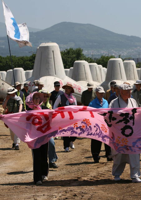 해군기지 건설 반대 ‘평화올레’ 참가자들과 평화와 통일을 여는 사람들(평통사) 회원들이 29일 오전 제주도 서귀포시 강정동 일대 해군기지 건설현장에서 펼침막을 들고 건설 반대 행진을 하고 있다. 뒤쪽으로 방파제를 만들 때 쓰는 테트라포드가 보인다.  서귀포/김태형 기자 xogud555@hani.co.kr