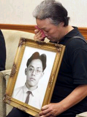 대만 공군 사병 장궈칭의 사형 집행 14년 만에 그에 대한 무죄 판결이 나온 뒤, 어머니 왕차이렌이 억울하게 숨진 아들의 영정을 가슴에 안고 눈물을 흘리고 있다.
 대만 <연합보> 누리집 갈무리