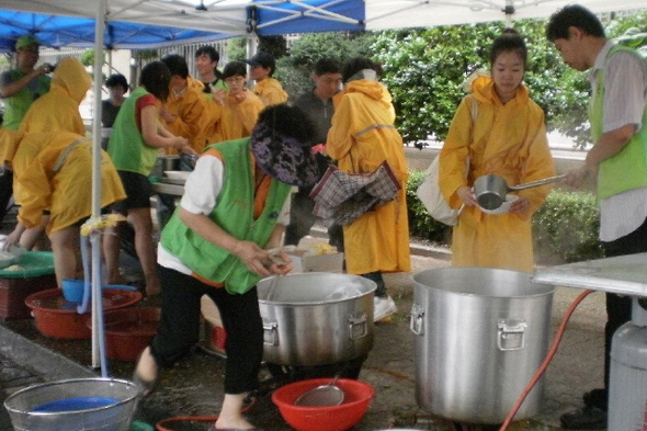  아름다운 국수가게를 운영하는 김혁(맨 오른쪽 국자 든 이)씨를 비롯한 ‘강북구 국수나눔봉사회’ 회원들이 지난 7월30일 서울 동작구 이수역 근처에서 집중호우 피해 복구에 참여한 자원봉사자들에게 만두공장의 자투리 만두피로 뽑아낸 ‘아름다운 칼국수’를 끓여 대접하고 있다.  서울시 자원봉사센터 제공