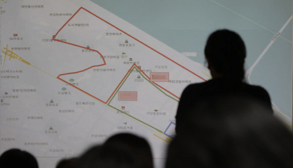 ‘공동통학구역’ 지정 결정으로 학생수가 줄어들어 사실상 폐교 위기에 놓인 서울 강서구 ㄱ중학교에서 관련 공청회가 열린 19일 오후 학부모들이 강서교육지원청 간부의 설명에 강하게 반대하는 모습이 슬라이드 화면에 그림자로 비치고 있다.  김봉규 기자 bong9@hani.co.kr