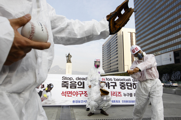 “석면야구장 한국시리즈 중단을” 방진복을 입고 방진마스크를 쓴 환경보건시민센터와 한국석면추방네트워크 회원들이 28일 오전 서울 광화문광장에서 석면이 포함된 사문석 흙이 깔린 인천문학경기장에서 열리는 삼성과 에스케이(SK)의 프로야구 한국시리즈 3, 4차전의 중단을 촉구하며 행위극을 벌이고 있다.  김정효 기자 hyopd@hani.co.kr