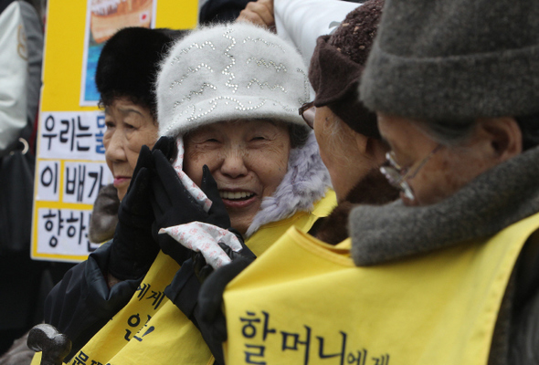 지난 2011년 12월 7일 낮 서울 종로구 중학동 주한 일본대사관 앞에서 열린 제999차 일본군 위안부 문제 해결을 위한 수요집회에 참석한 김순옥 할머니(왼쪽 둘째)가 핫팩을 얼굴에 대며 활짝 웃고 있는 모습. 신소영 기자 viator@hani.co.kr