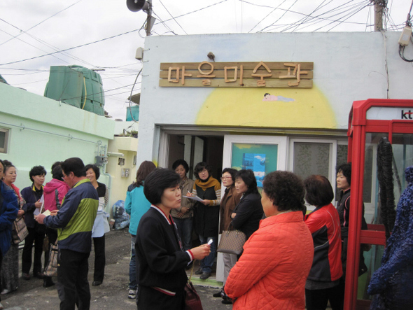 신화마을 아카이브전이 열리는 마을미술관 입구와 마을미술관 앞에 모여든 관광객들. 
 아트팩토리 신화 제공
