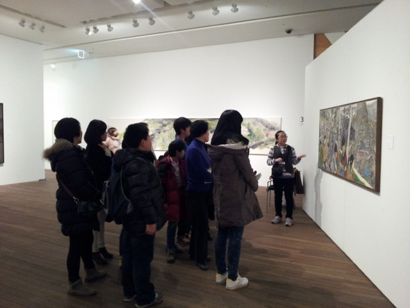 서울대미술관의 ‘교과서 속 우리 미술’전에서 초등학생 도슨트가 가족 관객들에게 최호철 작가의 작품 <을지로 순환선>에 대해 설명하고 있다.  서울대미술관 제공