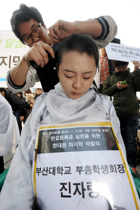 진자랑 부산대학교 부총학생회장을 비롯한 ‘21세기 한국대학생연합’(한대련) 소속 학생 대표들이 17일 오후 서울 청계광장에서 반값 등록금 실현을 요구하며 머리를 밀고 있다. 뉴스1