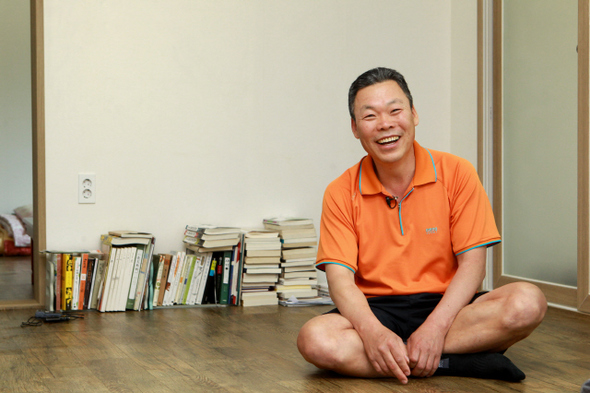 유용주 작가는 거실 바닥 소박하게 쌓인 책 앞에 앉아 환한 웃음을 지어 보였다. 이정아 기자
