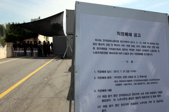 지난 2일 오후 경기 평택시 포승읍 만호리 만도공장 정문에 사측의 ‘직장폐쇄’를 알리는 공고문 게시판이 세워져 있다. 뒤쪽으로 경비용역업체 ‘지원가드’ 직원들이 정문출입을 통제하고 있는 모습이 보인다.  평택/김태형 기자 xogud555@hani.co.kr