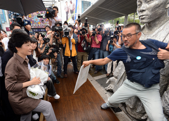 <b>전태일 찾은 박근혜…멱살잡힌 해고노동자</b>=박근혜 새누리당 대통령 후보가 28일 오전 서울 청계천 버들다리에 있는 전태일 동상에 꽃을 바치려는 순간 김정우 금속노조 쌍용차지부장이 팻말을 든 채 동상 앞을 막아서고 있다. 쌍용차 해고노동자인 김 지부장이 ‘쌍용차 문제해결을 외면하며 전태일 정신을 말하는 것은 대국민사기극이다’라고 적힌 팻말을 든 채 동상 앞에 주저앉자 경호원이 멱살을 잡아 끌어내려 하고 있다. 뉴스1