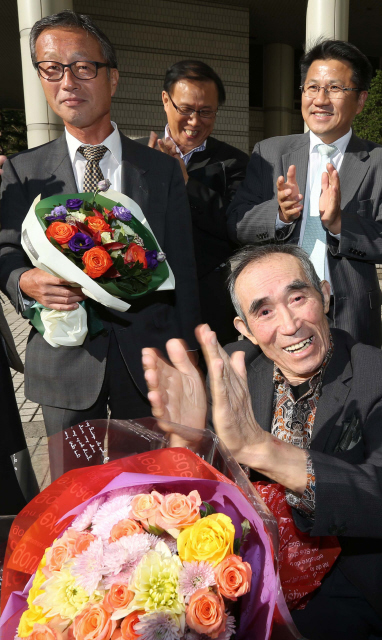  ‘재일동포 유학생 간첩사건’으로 실형을 선고받고 복역했던 고병택(앞쪽)씨와 허철중(맨 왼쪽)씨가 18일 오후 서울 서초구 서초동 고등법원에서 열린 재심에서 무죄를 선고받은 뒤 축하 꽃다발을 받고 환하게 웃고 있다.  류우종 기자 wjryu@hani.co.kr