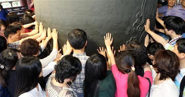 지난 7월 서울 종로구 관철동 보신각에서 열린 대학 합격기원 타종행사에 참석한 수험생과 가족들이 손으로 종을 만지며 소원을 빌고 있다.