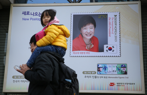 박근혜 대통령의 취임 한 달을 하루 앞둔 24일 오후 박 대통령 취임 기념우표 발행을 알리는 서울 광화문 우체국의 광고판 앞으로 시민들이 지나가고 있다.  김정효 기자 hyopd@hani.co.kr