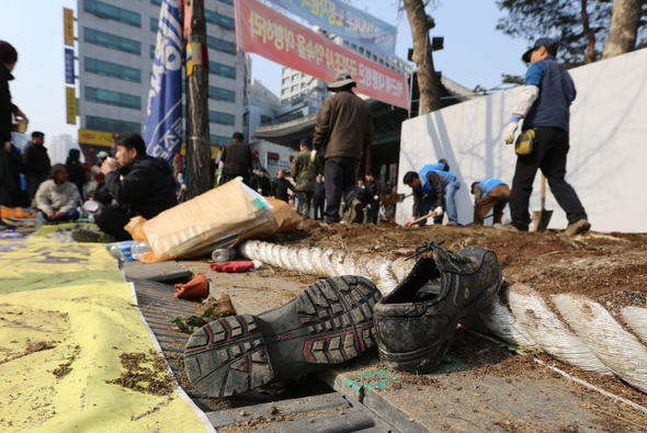 4일 오전 서울 덕수궁 대한문 앞에서 서울 중구청 직원들이 쌍용차 해고노동자들의 농성천막을 기습 철거한 뒤 대형 화단을 설치하고 있다. 화단 앞에 주인 잃은 신발이 널브러져 있다.  강창광 기자 chang@hani.co.kr