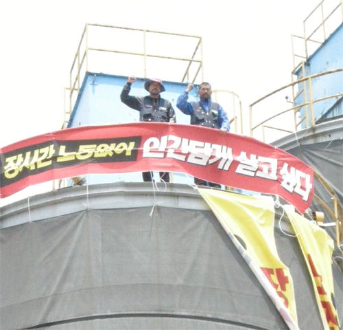 전국건설노조 울산건설기계지부 김낙욱(오른쪽) 지부장과 오명환(왼쪽) 부지부장이 20일 한라엔컴 울산공장의 시멘트 사일로 위에 올라가 고공농성을 벌이고 있다.