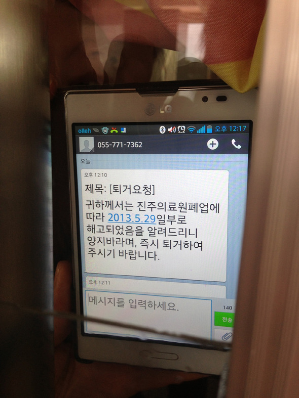 진주의료원 노조원들이 병원 문을 걸어잠그고 폐업철회를 요구하는 농성을 벌이고 있는 가운데, 30대 후반으로 보이는 여성 노조원이 한겨레 기자에게 유리창을 통해 해고통보 문자메시지를 보여주고 있다. /이정아 기자 leej@hani.co.kr