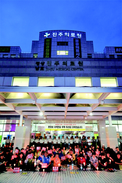 경남도가 진주의료원 폐업을 발표한 29일 저녁 전국보건의료산업노동조합 울산경남지역본부 조합원들이 진주시 초전동 진주의료원 본관 앞에서 촛불을 든 채 홍준표 경남지사를 비판하며 폐업 철회를 촉구하고 있다. 진주/이정아 기자 <A href="mailto:leej@hani.co.kr">leej@hani.co.kr</A>