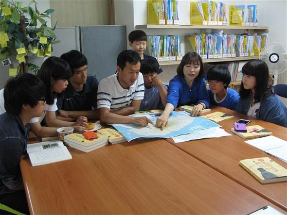 (왼쪽부터) 문병관군, 이다영양, 배민준군, 사공영익 팀장, 김주형군(위), 염철웅군, 김빛나 교사, 강지훈군, 이록비양이 제주도 지도를 살펴보며 여행을 준비하고 있다.