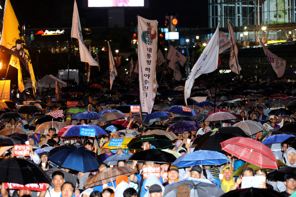 <b>국정원 규탄 10번째 집회</b> 지난 8월31일 저녁 서울역 광장에서 열린 ‘국가정보원 정치공작 대선개입 규탄 10차 범국민대회’에 참석한 시민들이 갑자기 소나기가 내리자 우산을 받쳐 든 채 국정원 개혁과 특검을 통한 국정원 대선개입 진상 규명 등을 촉구하고 있다. 류우종 기자 wjryu@hani.co.kr