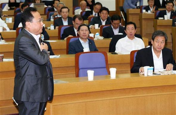 최근 우편향 논란을 빚고 있는 교학사 한국사 교과서의 주저자 이명희 공주대 교수(맨 왼쪽)가 11일 오전 국회 의원회관에서 열린 ‘새누리당 근현대 역사교실’ 모임에 강사로 참석해 연단으로 나가다 태극기를 보며 가슴에 손을 얹고 있다. 이 모임을 만들어 이 교수를 초청한 김무성 의원(맨 앞줄 앉은 이)이 그 모습을 지켜보고 있다.  뉴스1