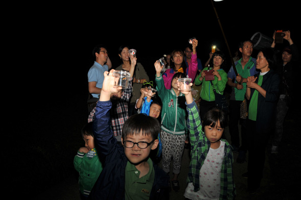 지난 15일 울산 울주군 범서읍 척과리 소불골에서 반딧불이 생태체험 행사에 참가한 어린이들이 반딧불이를 잡아넣은 병을 들어 보이고 있다.