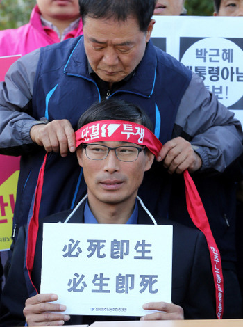 24일 오후 서울 세종로 정부서울청사 앞에서 전교조가 고용노동부와 교육부의 전교조 설립 취소에 항의와 향후 대책을 발표하는 기자회견을 하고 있다. 주봉희 민주노총 부위원장이 김정훈 전교조 위원장에게 머리띠를 매어주고 있다. 김태형 기자 xogdu555@hani.co.kr