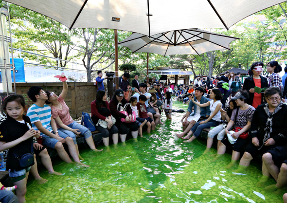 대전 유성구 봉명동 거리에 있는 족욕체험장에서 관광객들과 지역 주민들이 빼곡히 둘러앉아 온천 족욕을 즐기고 있다.