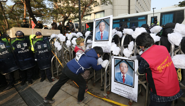 밀양송전탑 전국대책회의 회원들과 밀양에서 올라온 주민들이 20일 오후 서울 강남구 삼성동 한국전력 본사 앞에서 열린 ‘밀양 송전탑 공사 중단·고 유한숙 추모 기자회견’을 마친 뒤 고인을 추모하며 종이로 만든 조화와 영정사진을 출입문에 붙이고 있다. 스스로 목숨을 끊은 고 유한숙씨는 “살아서 그것(송전탑)을 볼 바에야 죽는 게 낫겠다. 그래서 송전탑 때문에 농약을 마셨다”는 유언을 남겼다.  김봉규 선임기자 bong9@hani.co.kr