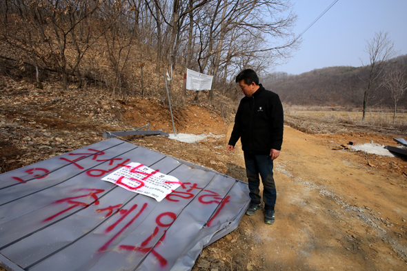 경기도 연천군 백학면 학곡리의 정현복 이장이 3일, 지난달 24일 민간 건설업자가 토지를 강제수용한 뒤 세운 철문을 주민들이 몰려가 무너뜨린 현장에서 당시 상황을 설명하고 있다. 땅바닥에 무너진 철문에는 주민의 요구사항이 적혀 있다.