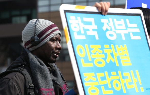 <b>“이주노동자 인종차별 철폐하라”</b> 유엔이 정한 ‘세계 인종차별 철폐의 날’을 하루 앞두고 시민단체 주최 기자회견이 열린 20일 오전 서울 종로구 세종로 광화문광장에서 한 이주노동자가 인종차별 철폐를 촉구하는 내용의 손팻말을 든 채 참석자들의 발언을 듣고 있다. 　신소영 기자 viator@hani.co.kr