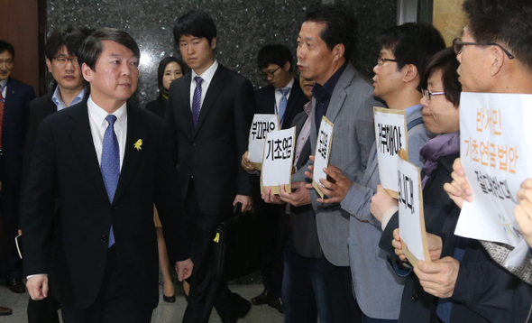 안철수 새정치민주연합 공동대표가 28일 오전 국회에서 기초연금법 개정 타협안 수용 여부를 논의하려고 열린 의총장으로 향하다, 입구에서 기초연금법안에 반대하는 시위를 벌이고 있는 시민단체 대표자들을 보고 있다. 이정우 선임기자